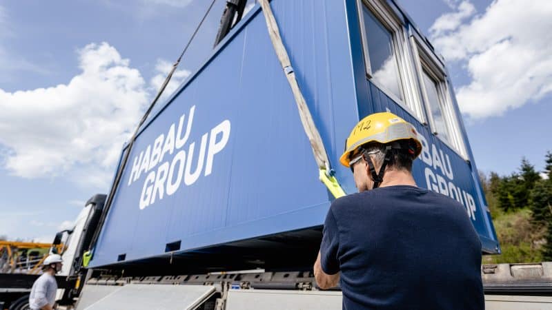 Beladung eines offenen Plateausattel LKW's mit einem blauen HABAU GROUP Container